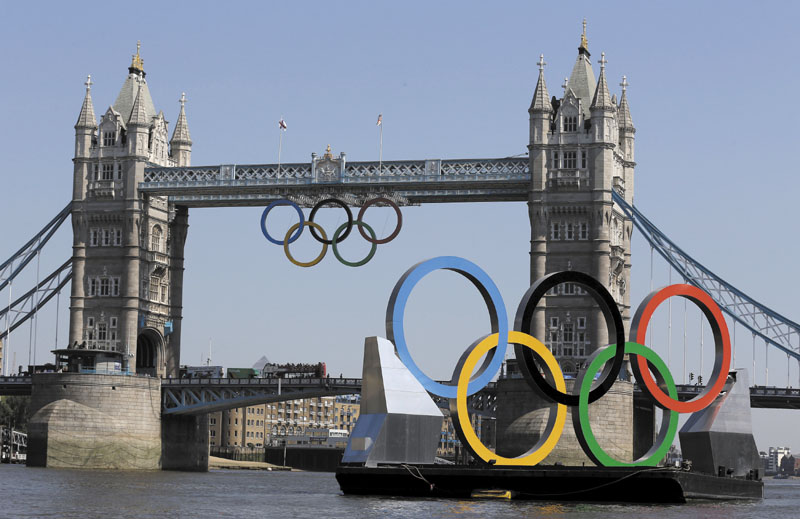 THE GAMES ARE HERE: Olympic Rings hang from the Tower Bridge beyond a set of rings floating on the River Thames on Thursday in London. The city will host the 2012 London Olympics with opening ceremonies scheduled for tonight. 2012 London Olympic Games;Summe