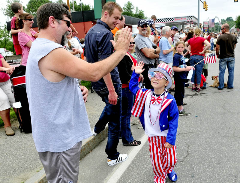 HIGH FIVE ON THE FOURTH: Dressed as Uncle Sam, Zachary Wentworth high-fives David Fuller during the Winslow Family 4th of July parade on Wednesday. Bay Street was packed with parade watchers.