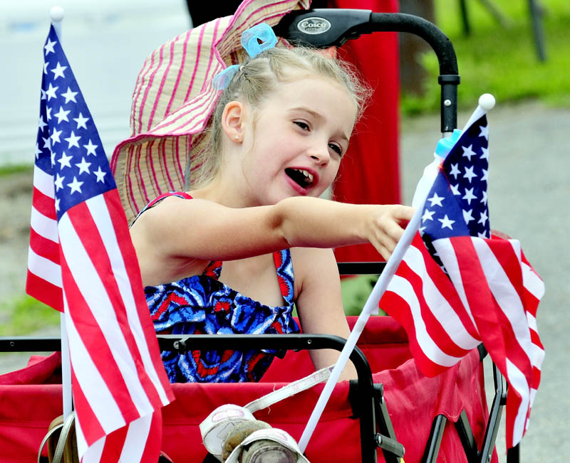 YOUNG PATRIOT: Between two American flags, Alexys Rolfe reacts as units go by in the Winslow Family 4th of July parade on Wednesday.