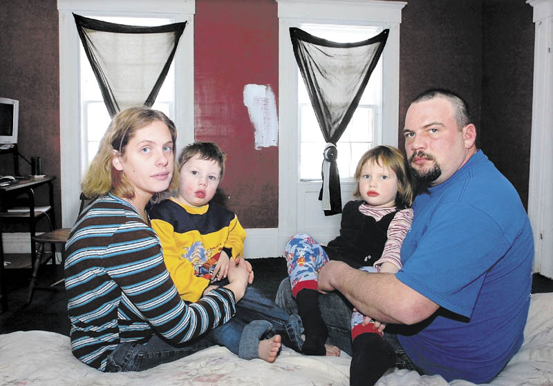 Paula Bratton and Dan Hills hold their children, Levi and Zoie, at the home they rent in Solon in 2008. The family says the exposed lead paint throughout the home has forced them to paint over walls, background, windows and floors where paint chips emerge to reduce exposure.