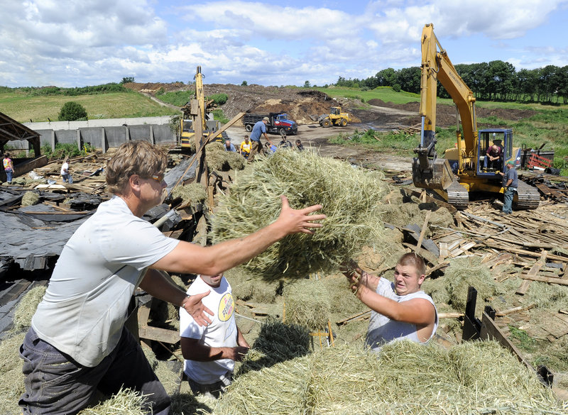 In this July 2010 file photo, Art McNeally, Jason Mitsin and Nate Faulkner load hay onto a truck at Benson dairy farm in Gorham. A novel program intended to raise money for financially strapped New England dairy farmers and educate consumers about the benefits of local farms is reorganizing after it had to pay more than $60,000 in back taxes.