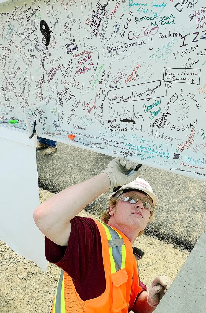 Staff photo by Joe Phelan Construction worker Tyler Bartlett autographs the final beam before it gets lifted into place before topping out ceremony on Monday morning at the construction site of Maine General Medical Center's new regional hospital in north Augusta.