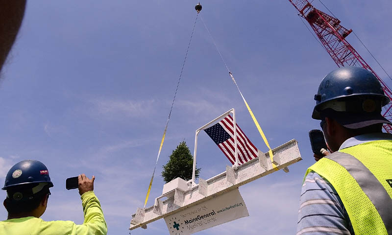Staff photo by Joe Phelan Workers record the final beam being lifted into place during the topping out ceremony on Monday morning at the construction site of Maine General Medical Center's new regional hospital in north Augusta. The beam was signed by many people and the tree was dug up from and will be returned to the site.