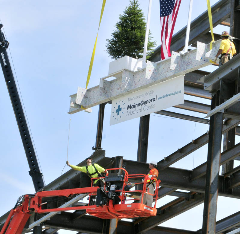 John Milbrand, construction manager for MaineGeneral Medical Center's new regional hospital, on right in lift, puts in the bolts on the final beam during the topping-out ceremony Monday morning at the construction site in north Augusta. The beam was signed by many people, and the tree was dug up from and will be returned to the site.