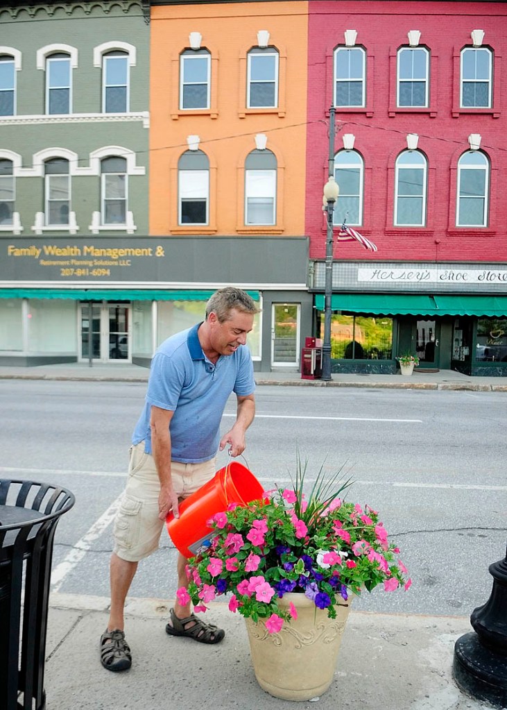 Larry Fleury waters a planter on Water Street on Thursday evening in downtown Augusta. The Augusta Downtown Alliance has installed over fifty planters and hanging baskets on the street.