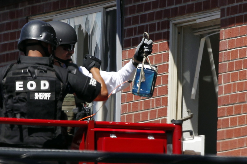 Members of law enforcement wearing body armor and helmets prepare to what ATF sources describe as a"water shot" in the apartment of alleged gunman James Holmes today. The "water shot" is exploded and used to disrupt the device.