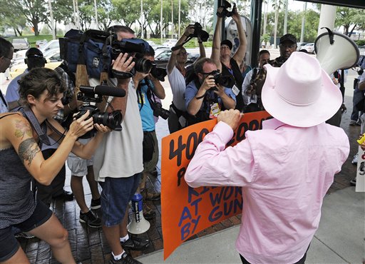 Photographers work as a Code Pink demonstrator speaks at a venue where former Secretary of State Condoleezza Rice was to speak, Tuesday, Aug. 28, 2012, in Tampa, Fla. Protestors gathered in Tampa to march in demonstration against the Republican National Convention. (AP Photo/Mike Stewart)
