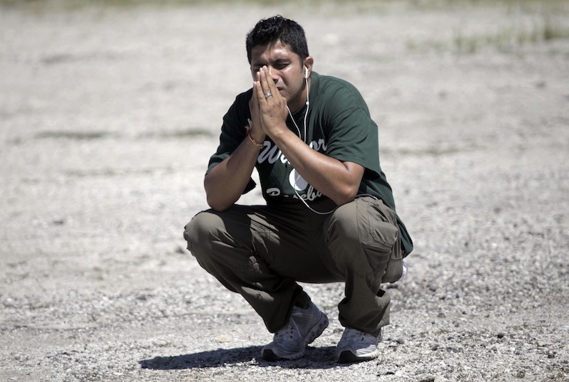 Amardeep Kaleka, whose father, Satwant Singh Kaleka, the president of the Sikh Temple of Wisconsin, was shot and currently being treated in the hospital, kneels down in a parking lot near the scene where the shooting occurred, Sunday, Aug. 5, 2012, in Oak Creek, Wis. At least six people were killed Sunday when a gunman opened fire at the Milwaukee-area temple, and the suspected shooter later died in an exchange of gunfire with police, authorities said. (AP Photo/Milwaukee Journal-Sentinel, Mike De Sisti)