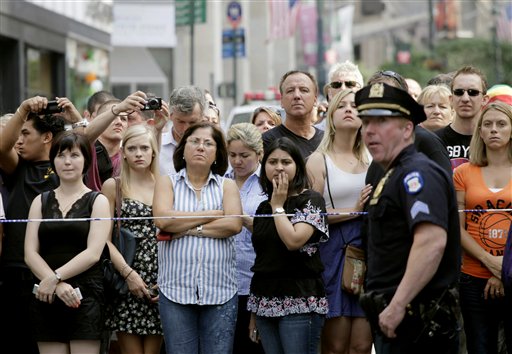 Bystanders and a police officer stand on Fifth Avenue to view the scene after a multiple shooting outside the Empire State Building, Friday in New York.