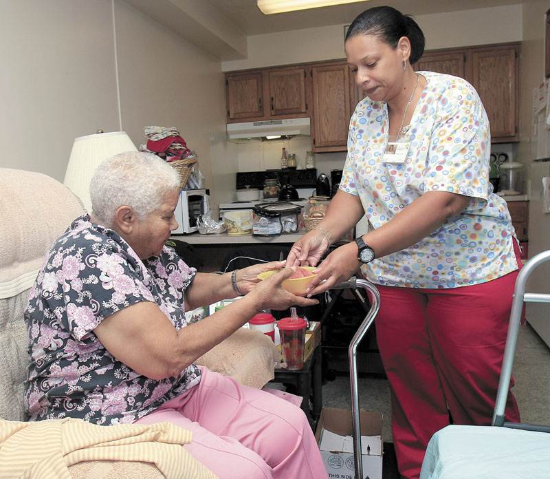 Taura Tate, right, a home care aide since 1999, hands cut watermelon to Crell Johnson, 76, on Wednesday at Johnson’s apartment in Euclid, Ohio. For the past three years, she has spent four hours each weekday morning caring for Johnson, who suffered a stroke and has diabetes. Tate cooks Johnson's oatmeal for breakfast, helps her shower and makes sure she takes the right medication.