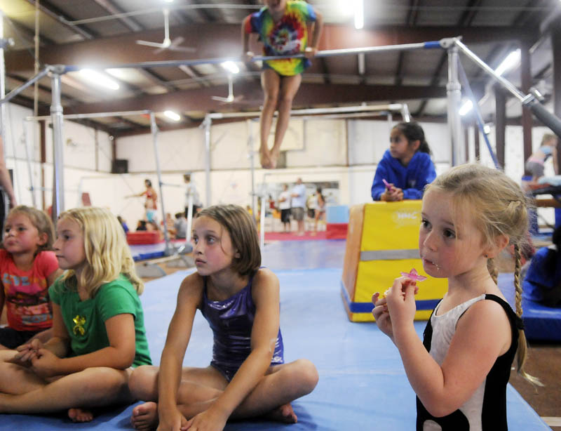 STAFF PHOTO BY ANDY MOLLOY RAISING THE BAR: Cariana Rollins eats a cupcake Tuesday at Mainely Gymnastics in Augusta while watching the Olympics. Gymnasts had a party at the gym to celebrate the games.