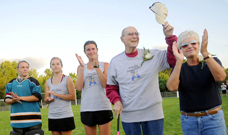 HATS OFF: Cony High School field hockey honorary captain "Doc" John Cameron salutes the crowd Tuesday evening at Gardiner Area High School before the Drive Out Cancer Challenge field hockey game between Cony High School and Gardiner High School. Cameron, 87, of Augusta was escorted onto the field by his wife, Linda, right, granddaughter, Cony field hockey coach Holly Daigle, center, and field hockey captains Kevie Rodrigue, left, and Jenna Harwood.