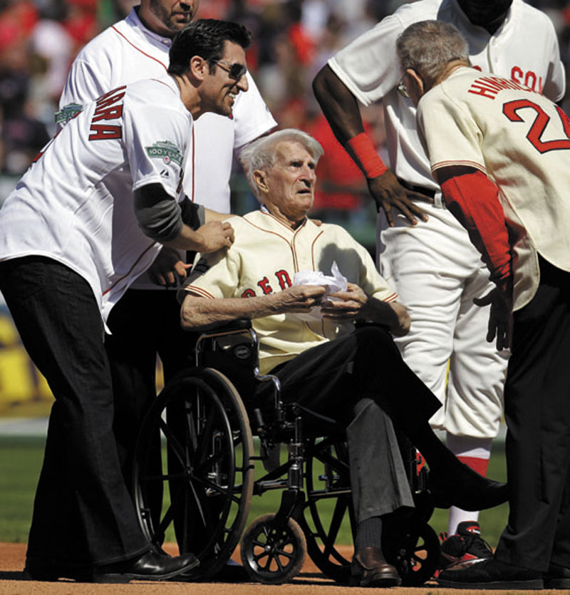 Boston Red Sox great Johnny Pesky, center, is greeted in April by former player Nomar Garciaparra, left, and others during a celebration of the 100th anniversary of the first regular-season baseball game at Fenway Park prior to the Red Sox taking on the New York Yankees in Boston. Pesky, who spent most of his 60-plus years in pro baseball with the Red Sox and was beloved by the team's fans, died on Monday, in Danvers, Mass. He was 92.