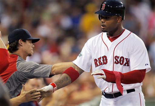 Boston Red Sox's Carl Crawford is welcomed to the dugout after scoring on a double hit by Adrian Gonzalez in the third inning Monday at Fenway Park in Boston.