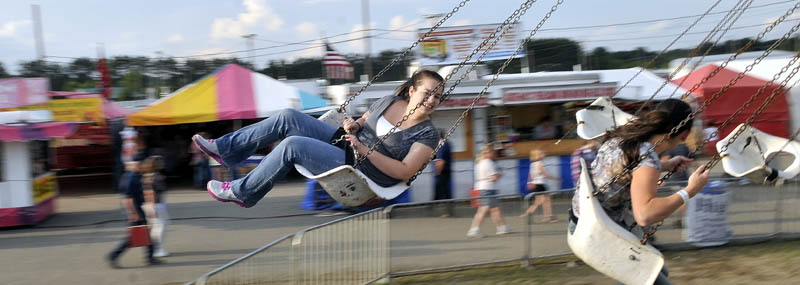 Staff photo by Michael G. Seamans Krista Rogers, 19 left, and Megan Miville, 19, both of Fairfield, spin around on the Trapeze Swings at the Skowhegan State Fair Wednesday.
