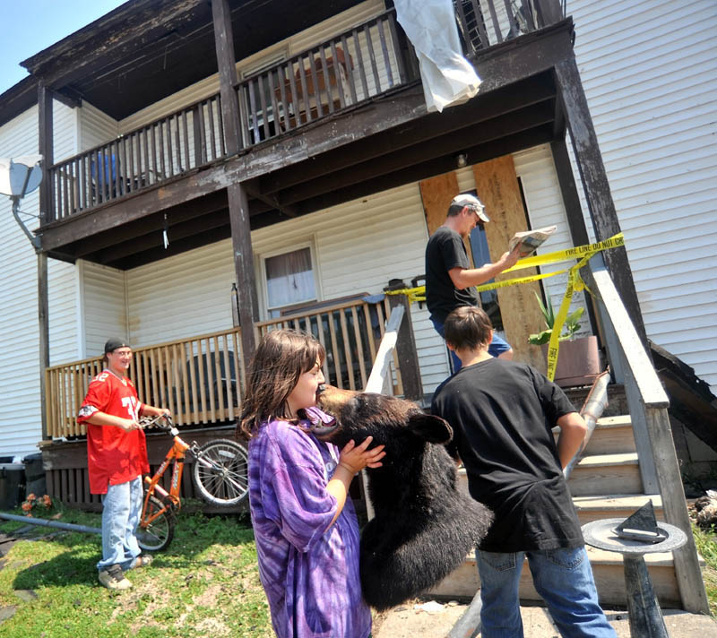 Brooke Robinson, front center, kisses the head of a bear that was salvaged from Jeff White’s, far back, apartment as they sort through salvageable belongings from their apartment on Drummond Avenue in Waterville on Thursday.