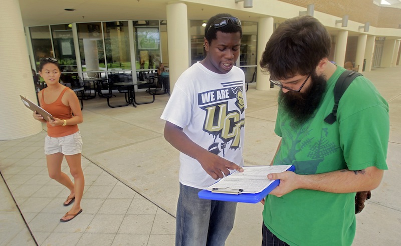 In this July 31, 2012, photo, Aubrey Marks, left, watches Jordan Allen, center, as he helps student Casey Eirhstaedt, right, register to vote at the University of Central Florida in Orlando, Fla. While most college campuses are relatively quiet, students at the University of Central Florida have taken it upon themselves to register their peers during the summer. Gone are the days when young voters weren’t taken seriously. In 2008, they helped propel Barack Obama into the Oval Office, supporting him by a 2-1 margin. But that higher profile also has landed them in the middle of the debate over some state laws that regulate voter registration and how people identify themselves at the polls. (AP Photo/John Raoux)
