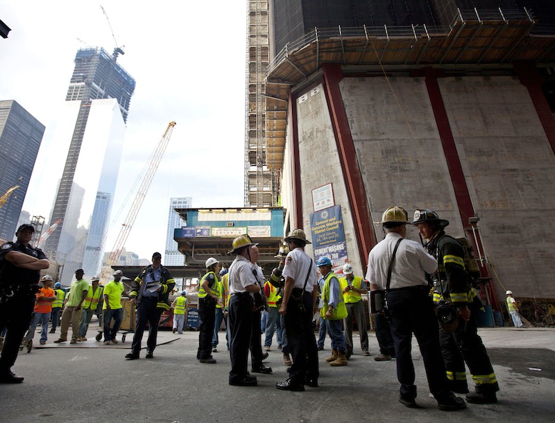 New York City firefighters gather at the base of One World Trade Center, right, where they were summoned by a report of a fire that turned out to be someone welding, Wednesday, Aug. 8, 2012, in New York. The fire department says it received a report of a fire on the 88th floor of One World Trade Center at ground zero shortly before 8 a.m. but a spokesman for the Port Authority of New York and New Jersey, which owns the site, said the report, by a member of the the public, was believed to be a false alarm. (AP Photo/Jin Lee)