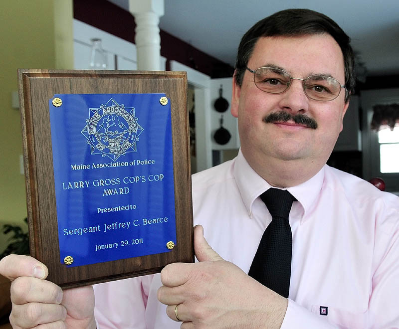 Waterville police Sgt. Jeffrey Bearce holds the Larry Gross Cop’s Cop Award he received in February 2011. The state's human rights panel says Bearce was subject to illegal workplace discrimination.