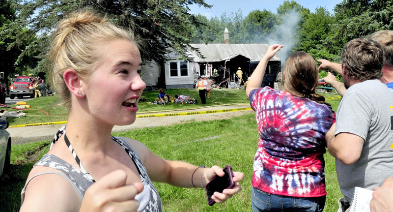 Babysitter Amanda Garboski recounts her reaction after discovering fire in this home on the Smithfield Road in Belgrade on Monday. Angelia and Kevin Tozir point as firefighters extinquish the stubborn blaze, Garboski got two children and a dog out safely.