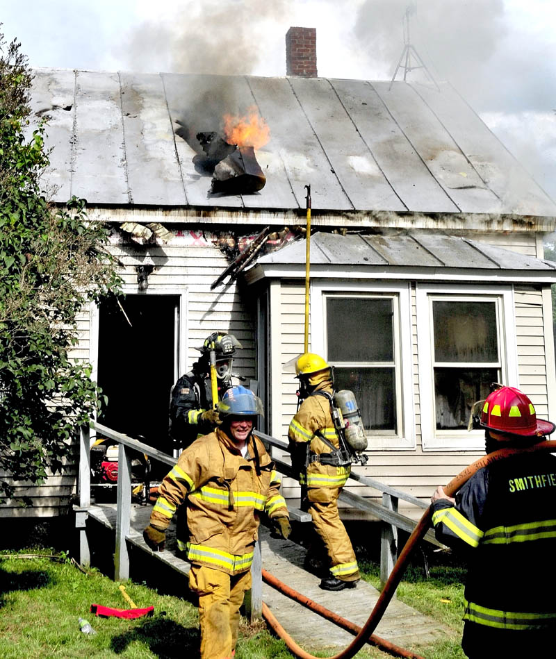 Flames shoot up through the roof of a home on the Smithfield Road in Belgrade that was destroyed by fire on Monday. The stubborn fire began in the rear of the building and eventually moved to the front despite the efforts of firefighters from six departments.