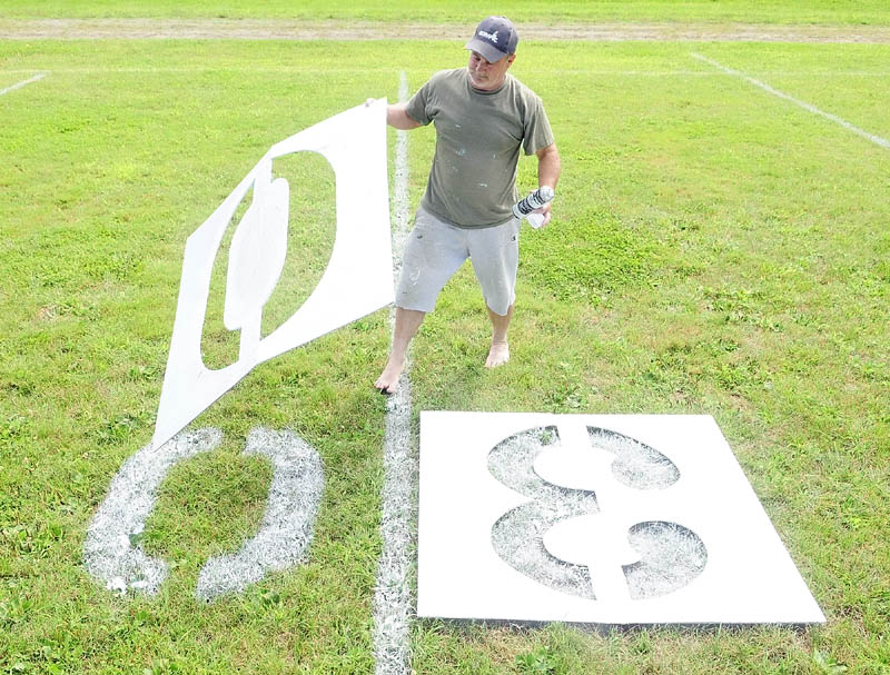 JUST RIGHT: Bruce Brooks lifts up a stencil after spray painting a zero last week on Maxwell Field where the Winthrop Ramblers play football games. The Ramblers open their season tonight on the road against Sacopee Valley in Hiram.