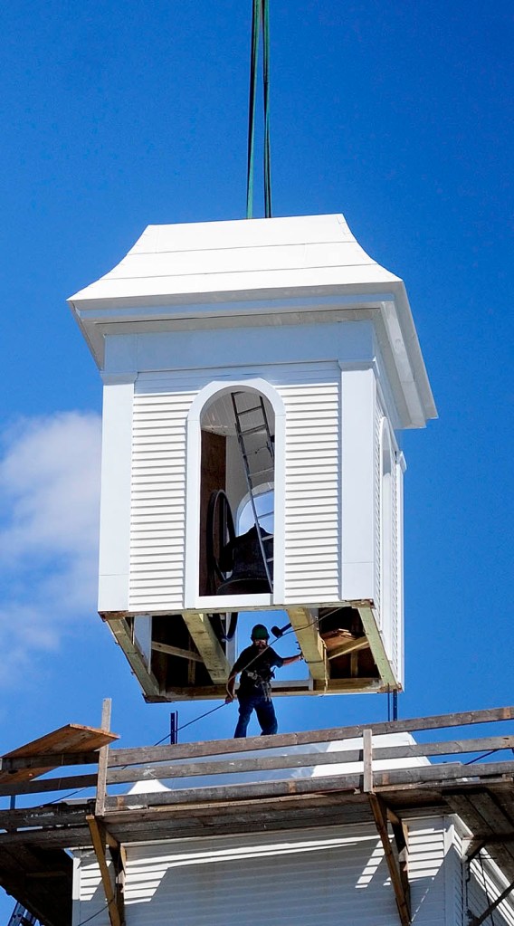 A crane lowers the bell tower that steeplewright Robert Hanscom built on to the steeple on Tuesday morning at the corner of Middle and Central streets in Hallowell.