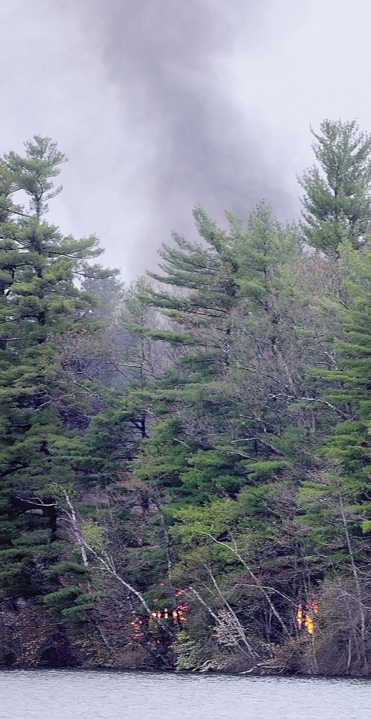 Smoke rises from a structure fire on an island in Togus Pond on Friday evening.