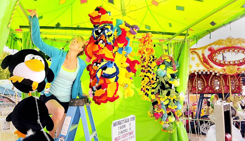 Kate Miller hangs up prizes at her Maggie's Duck Pond game booth on Sunday morning at the Windsor Fairgrounds. The Windsor Fair continues through Labor Day and the fairgrounds are located on state Route 32 near the intersection of state Route 17.