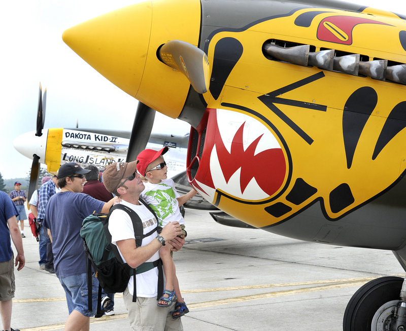 Ty Giberson of Dixfield and his 4-year-old son, Mitchell, check out a World War II P-40 fighter owned by the Texas Flying Legends Air Museum at the air show on Saturday.