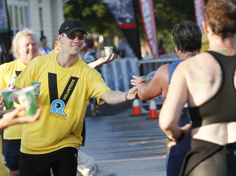 Stephen Gagnon of Portland and Jeanette Strickland of Westbrook, part of a group of volunteers from the Maine Masters Swim Club, hand out water to competitors during the Revolution3 triathalon in Old Orchard Beach on Sunday.