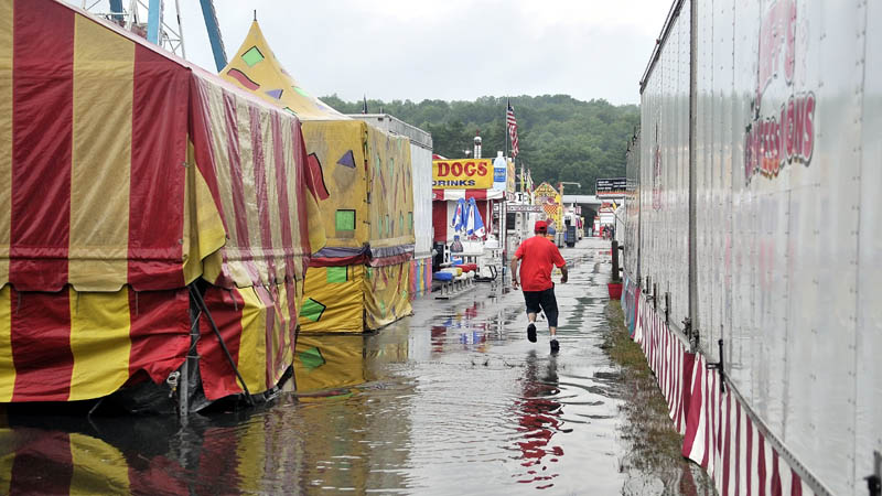 A fair worker triple jumps over a puddle t the Skowhegan State Fair friday morning.