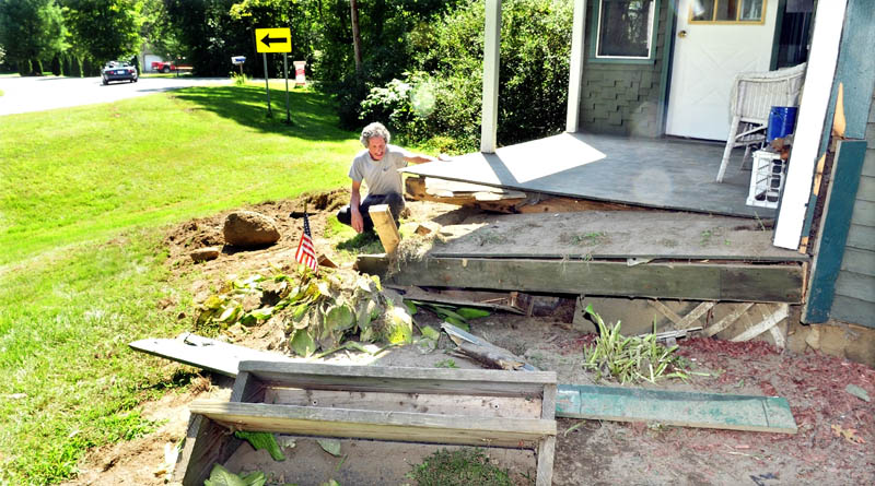 A vehicle drives around a sharp curve on the Hill Road in Canaan as homeowner Robert Spencer examines the damage to his front porch after a truck veered off the road early Monday. Spencer said he woke to squealing tires and the house shook after a truck slammed into his home, injuring two men in the vehicle.