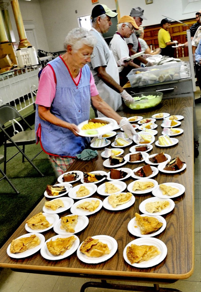 Patricia Stewart and other volunteers serve lunch at the Sacred Heart Soup Kitchen in Waterville on Monday. A flood of donations will keep the soup kitchen open to January.