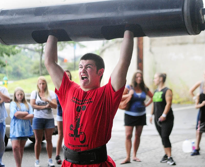 STRENGTH: Cody Drummond, of Augusta, strains to lift the bar overhead in the log clean and press event during the Downtown Throwdown strongman contest on Front Street Saturday morning in downtown Augusta.