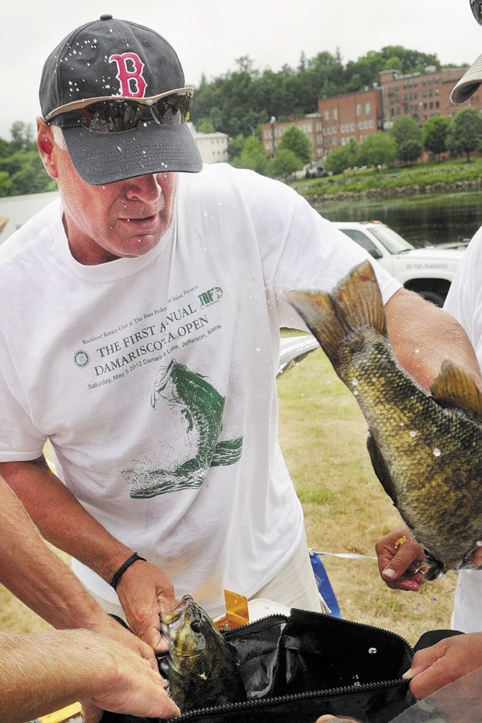 Dave Austin, of Augusta, loads fish into a bag to be weighed at the end of the Augusta Fest bass fishing tournament on Saturday at the East Side Boat Landing. Austin and his partner, Chris Brewer, of Livermore, beat seven other teams with a total of 11.03 pounds for their seven fish entered. Most Augusta Fest events, except for this and the strongman-style contest held earlier in the morning, were canceled because of the weather.