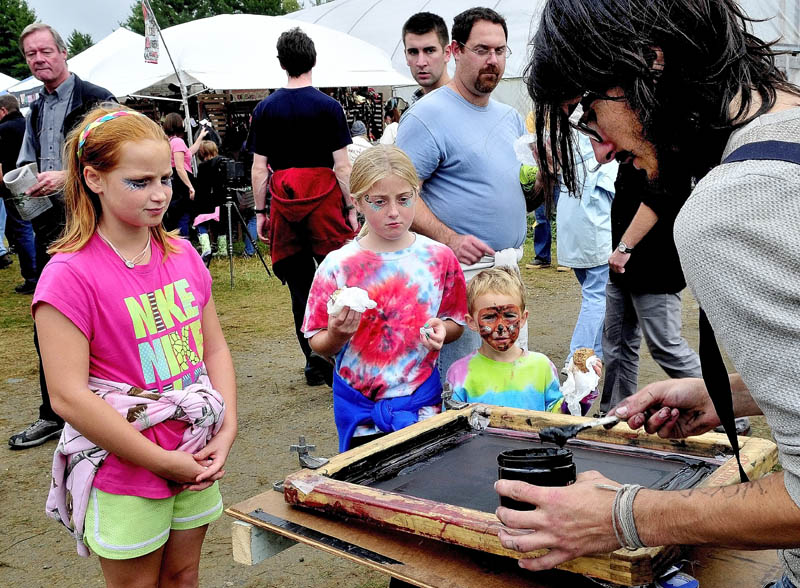 CONTRAST: Payrn Oak demonstrates black and white silk screen printing as a colorful trio of kids watch at the Common Ground Country Fair in Unity on Saturday. From left are Bella Russo, Shauna Hancock and Nico Russo.