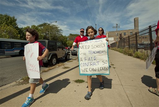 Children holding posters supporting striking teachers join a large group of public school teachers as they march on streets surrounding John Marshall Metropolitan High School on Wednesday in West Chicago.