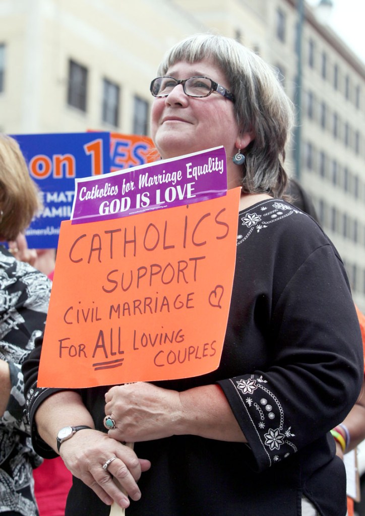 Kathy Tosney holds a sign as she listens to speakers Monday at a rally outside of City Hall in Portland, in support of a ballot question that seeks to legalize same-sex marriage.