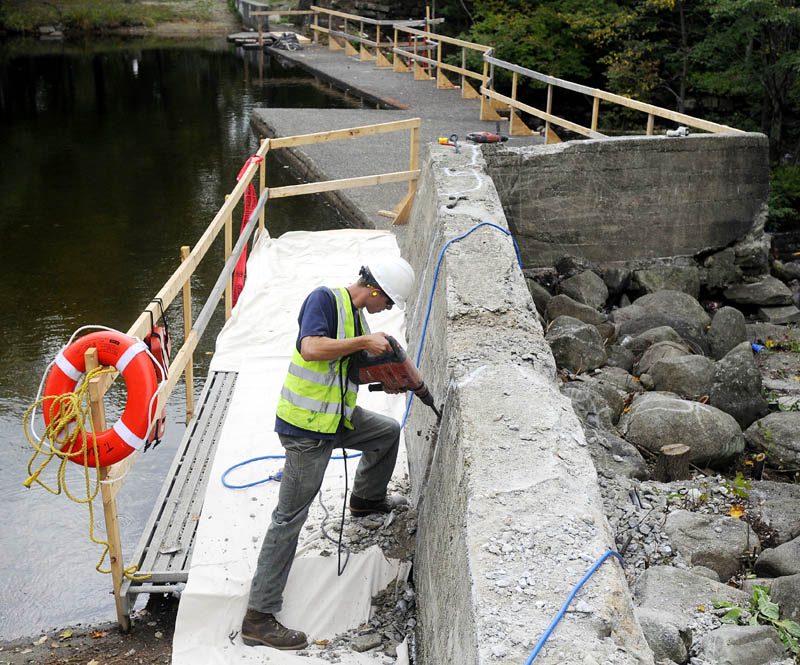 TOUCH UP: Jack Parshall saws a fissure Tuesday into the concrete wall of the North Wayne Dam in Wayne as part of the town's repair of the impoundment. Workers from T Buck Construction, of Auburn, plan to repair cracks in the concrete and replace the stop logs in the dam.