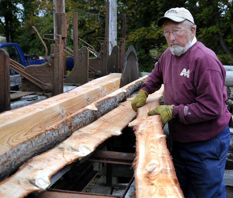 SPLIT: Freeman Lord lugs a slab of hemlock he cut Wednesday at his family's Hallowell saw mill. Lord is cutting beams for a barn he plans to assemble with wood from the family's lot. The mill was built by his father, Roger, the same year Freeman was born, 1940.