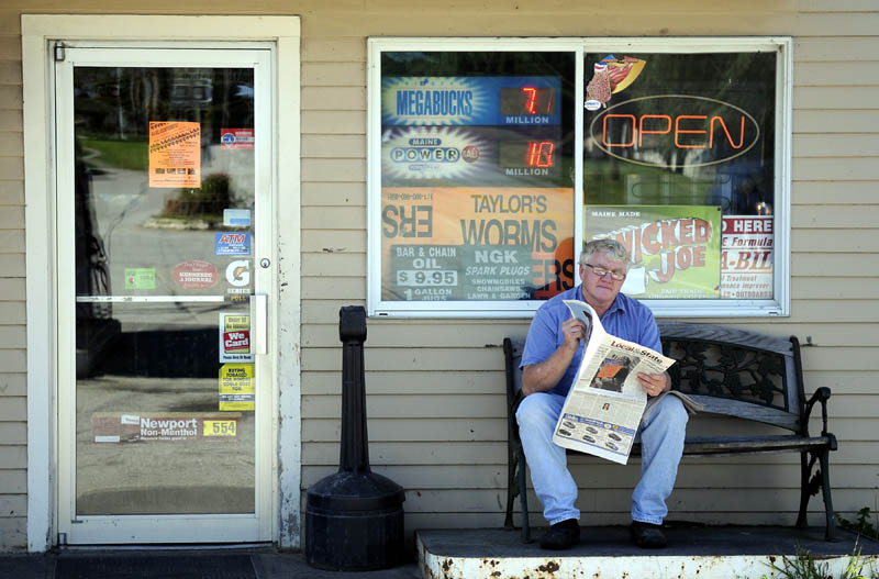 DOWN TIME: Mark Rush catches up on local news Tuesday while taking a break from the register at Randolph Take Out. Rush said the exterior paper break was a good way to experience the mild weather.