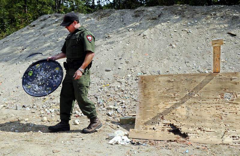 District Game Warden Steve Allaire collects garbage Thursday from the public target range on state land in the Summerhaven pits in Augusta. Allaire removes several hundred pounds of debris from the range each month.