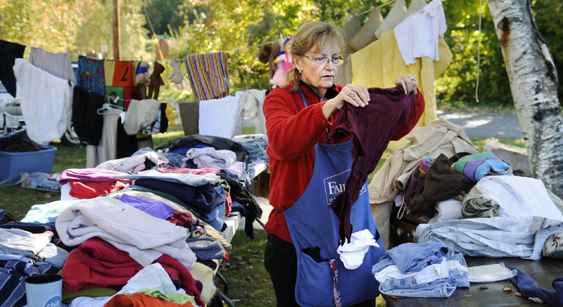 LAWN SALE FUNDRAISER: Barbara Veregge folds clothes Sunday at a lawn sale in Gardiner that raised funds for the treatment of 12-year-old Brandon Ware. The Gardiner child was diagnosed in Boston with a benign tumor on his brain stem.