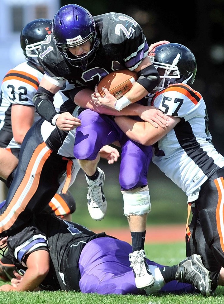 FIGHTING FOR YARDS: Waterville Senior High School running back Racean Wood, center, is tackled by Gardiner’s Jory Vermillion, right, in the second quarter of the Tigers’ 21-18 win Saturday in Waterville.