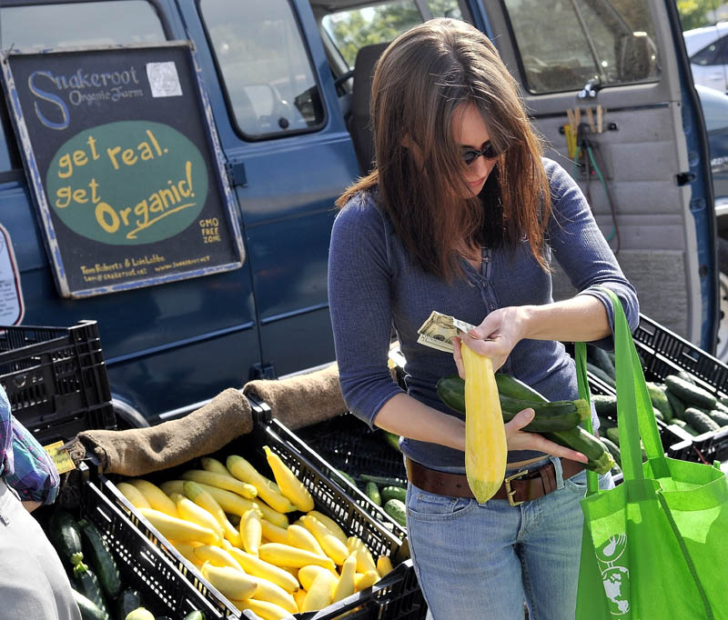 Kassandra Weese, of Albion, selects some cucumbers and squash from the Snakeroot Organic Farm stand at the Waterville farmers market at The Concourse on Thursday afternoon. A new study released suggests that organic foods have no more nutrients than conventionally grown vegetables. Weese said, “I buy organic food for two reasons: to avoid pesticides and buy locally.”