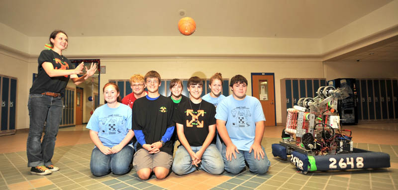 Mike the robot shoots a basketball to Kenzie Brunell, far left standing over members of the Messalonskee High School robotics teammates at Messalonskee High School in Oakland Thursday. Team members kneeling are from left to right Sabine Fontaine, Kenzie Brunelle, Bradley Bickford, Brady Snowden, Amy Pinkham, Robert Klein, Alex Dyer and Justin Shuman.