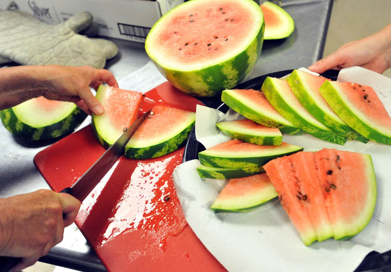 Nancy Holland cuts fresh watermelon for desert at the harvest dinner at Garrett Schenck Elementary School in Anson.