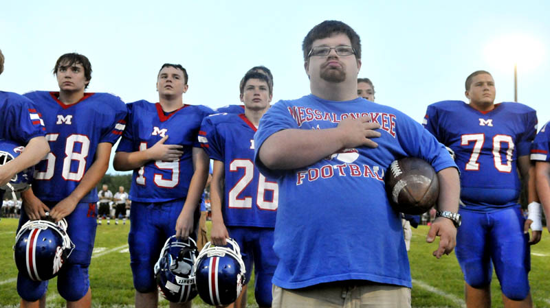 COACH TREVOR: Trevor Perry, front center, stands in front of the Messalonskee High School football team with his hand over his heart during the playing of the national anthem before the Eagles hosted Skowhegan on Friday night in Oakland.
