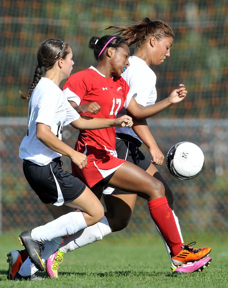 SANDWICHED: Winslow High School’s Autumn Poulin, left, and Alliyah Veilleux, right, battle an unidentified Camden Hills player in the second half of the Black Raiders 4-0 win on Thursday in Winslow. Poulin and Veilleux each scored a goal.